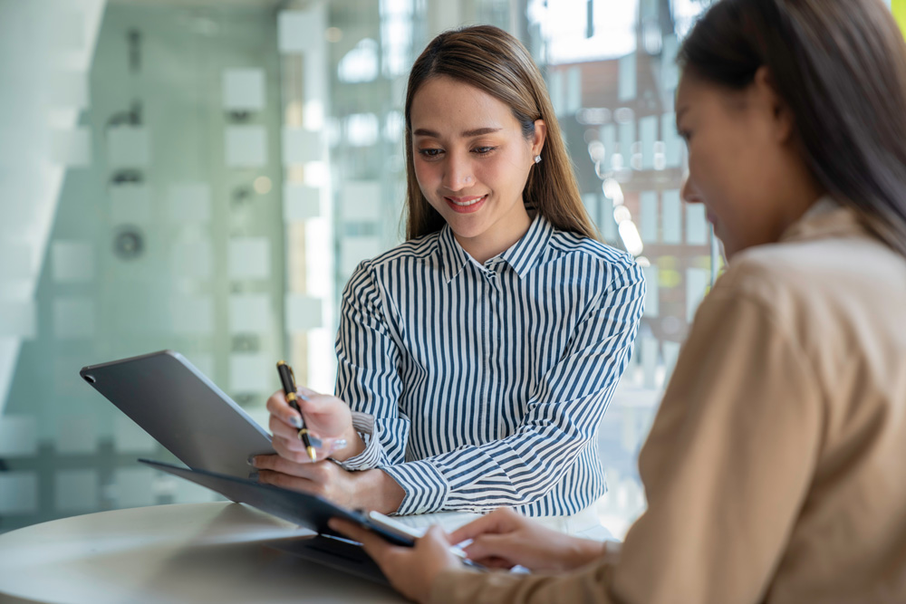 two ladies sitting at table looking over a document